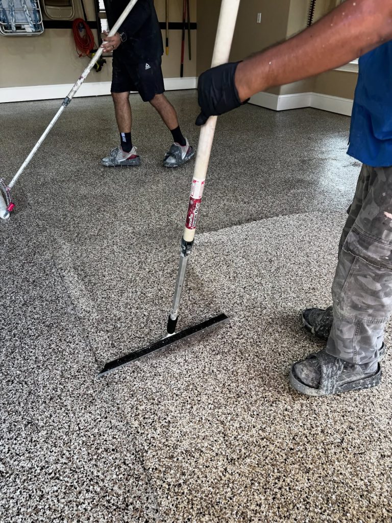 Floor Shield crew spreading the base coat on a garage floor